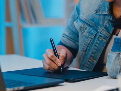 cheerful-young-graphic-designer-lady-using-digital-graphic-tablet-while-working-late-modern-office-night-asia-professional-female-using-laptop-computer-retoucher-sitting-living-room-home